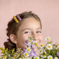 yellow and lilac hair barrettes in a low bun hairstyle for girls. cute summer or spring picture idea with wildflowers.