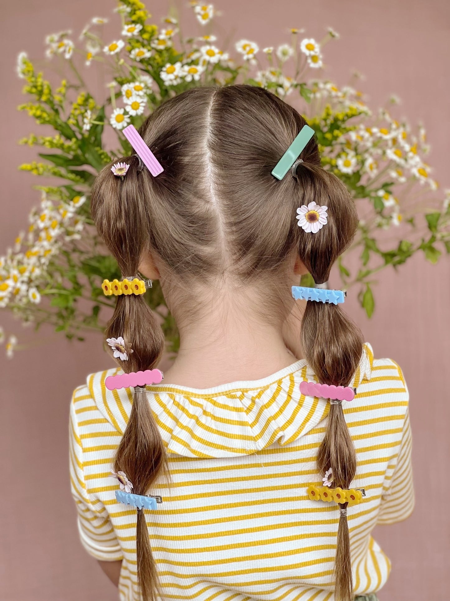 double pony tail hair style with daisies. Pony tails are sectioned with hair barrettes clipped throughout. adorable and colorful hair style.